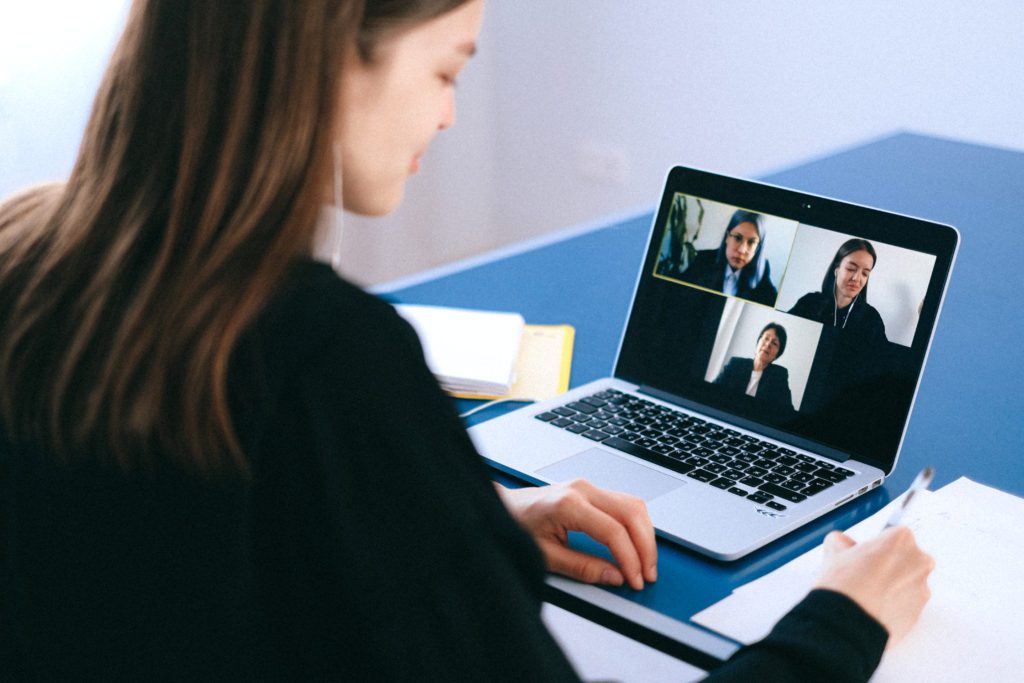 A woman is on her laptop and has two people in the background.