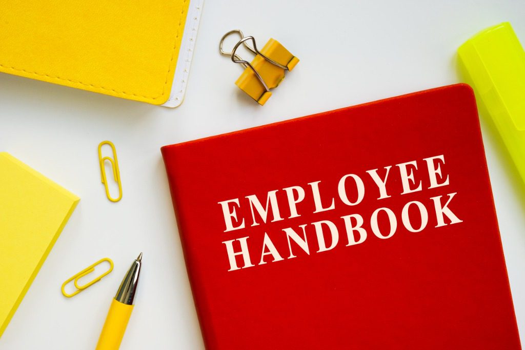 A red book with the words " employer handbook ".