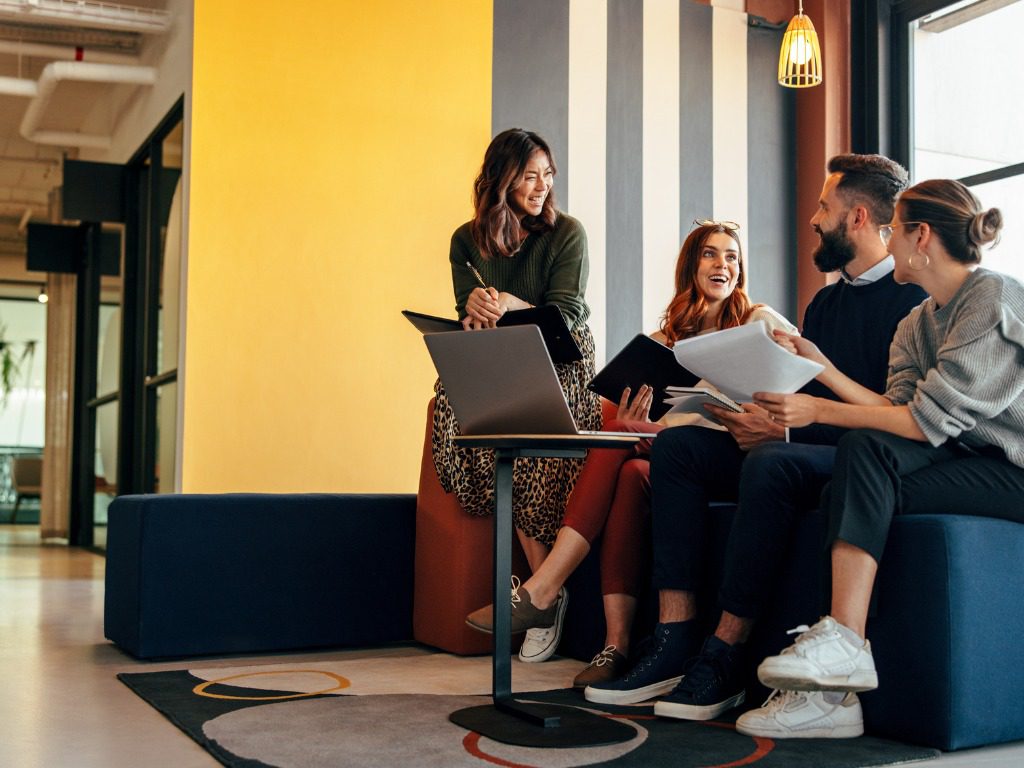 A group of people sitting around a table with laptops.