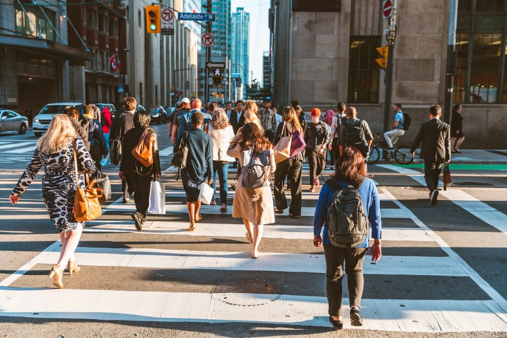 A group of people crossing the street in a city.