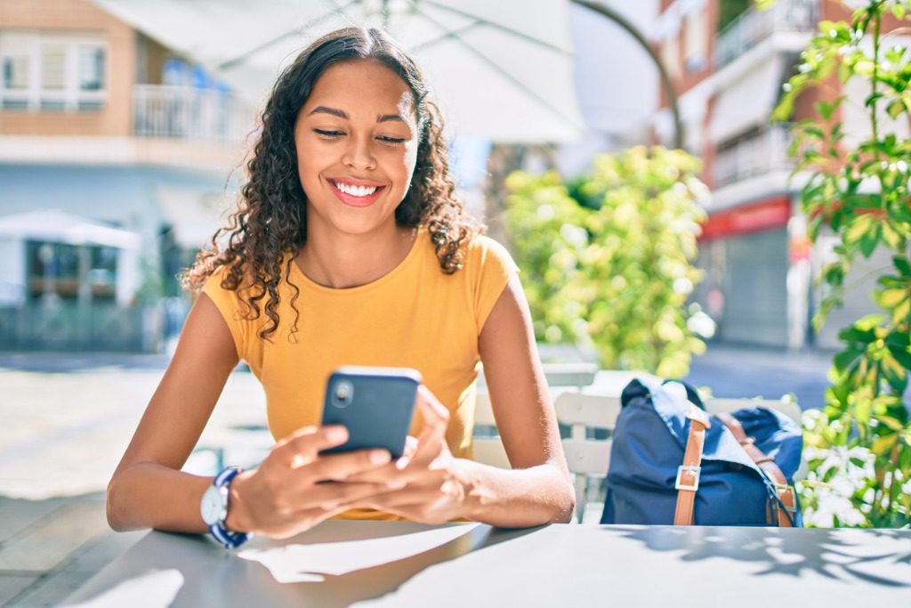 A woman sitting at an outdoor table looking at her phone.