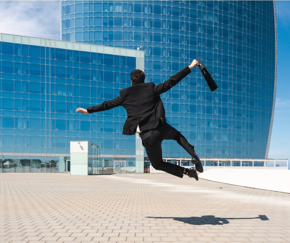 A man in black suit jumping in the air.