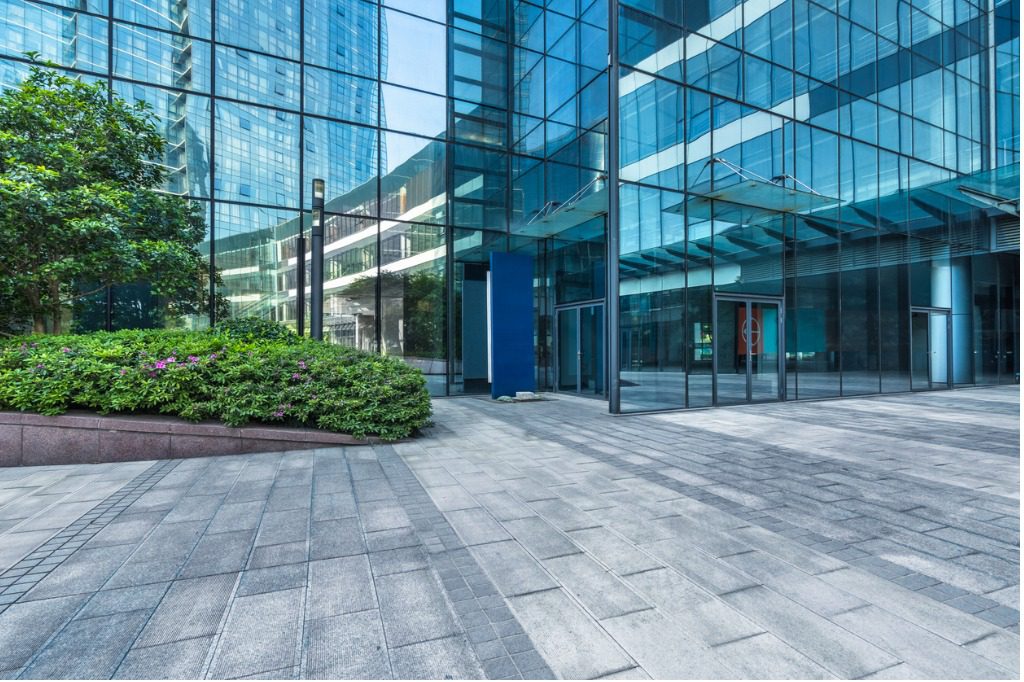 Modern glass building with gray pavement.