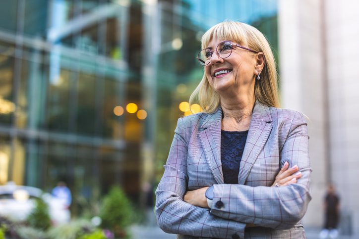 Smiling woman in glasses and blazer.