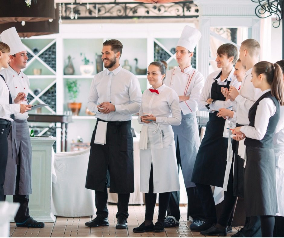 Restaurant staff in white and black uniforms.